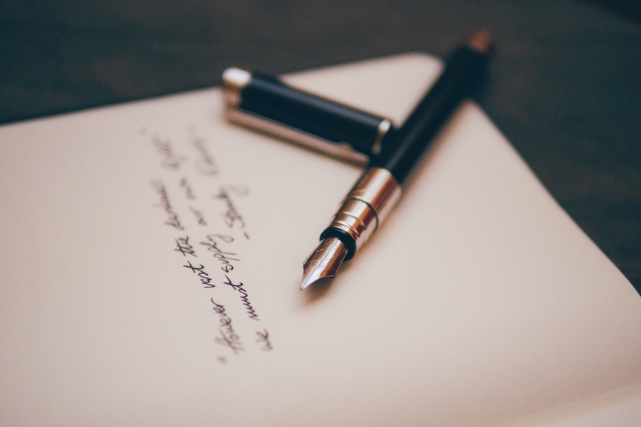 Uncapped fountain pen on a sheet of paper under some cursive writing